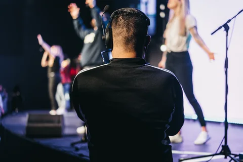 A camera operator wearing headphones films the worship team onstage at Radiant Church.