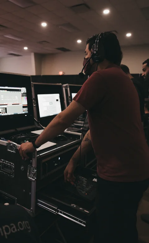 A production team member wearing a headset works at monitors and control equipment overlooking a Radiant Church auditorium.