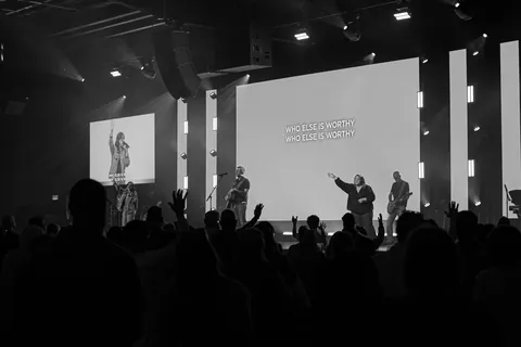 A black-and-white view of the worship team, screens, and congregation at Radiant Church’s Spring Hill location.