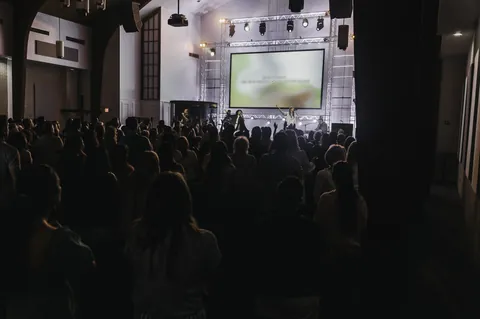 A wide view of the stage, lighting truss, projection screen, and congregation at Radiant Church’s West St. Pete location.